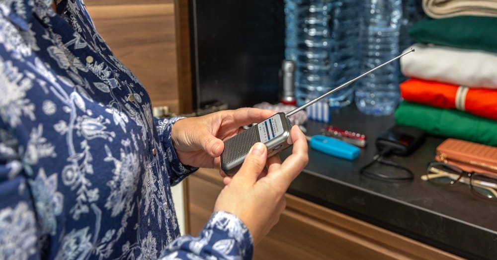 Vrouw stemt een draagbare radio af naast haar noodvoorraad
