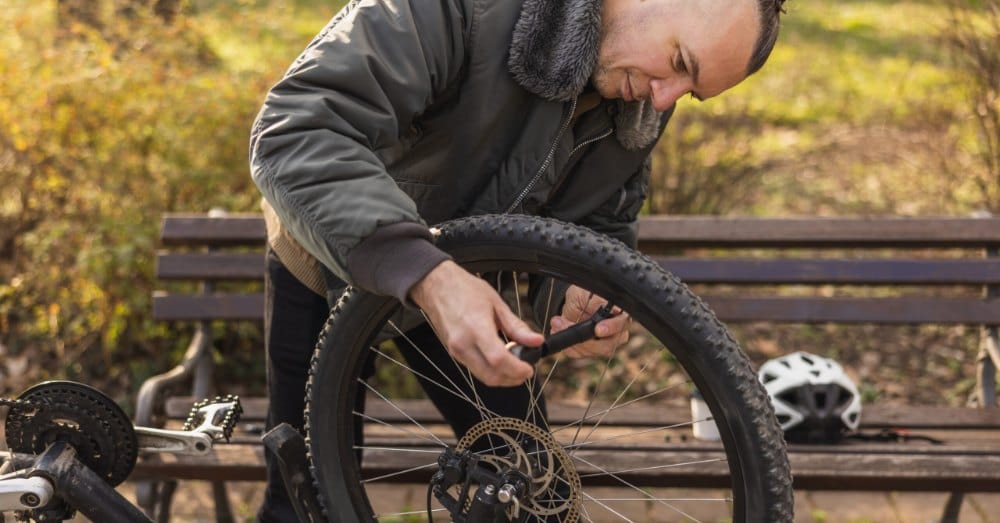 Man pompt de band van zijn fiets op in het park